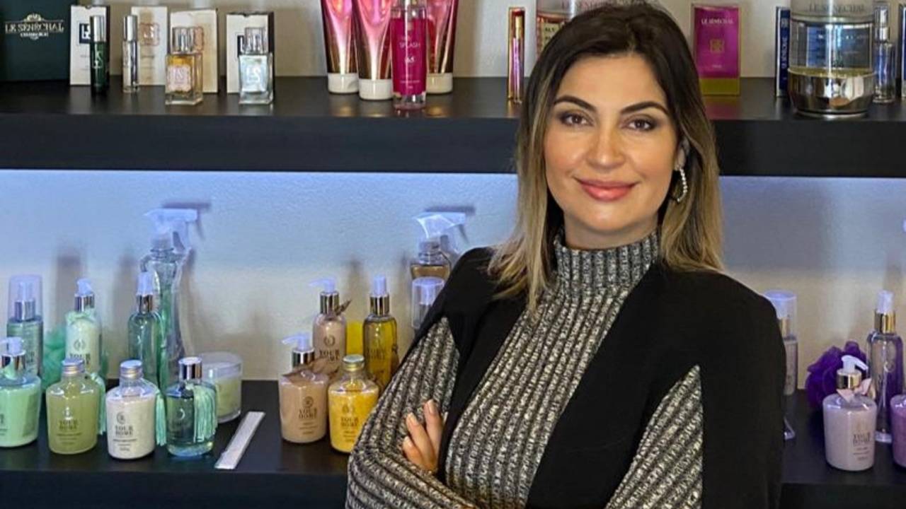 Thamis Le Sénéchal em frente a uma estante com os produtos Le Sénéchal.